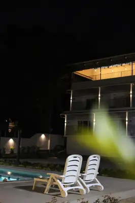 two white chairs sitting next to a pool at night at Seeheim Resorts in Athirappilly