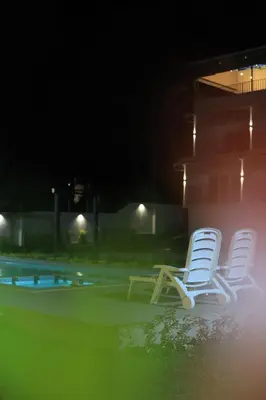 two chairs sitting next to a pool at night at Seeheim Resorts in Athirappilly