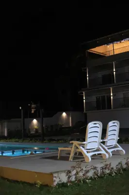 two lounge chairs sitting next to a swimming pool at night at Seeheim Resorts in Athirappilly