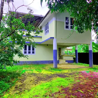 a white house with blue columns in a yard at Empire HomeStay in Kalpetta