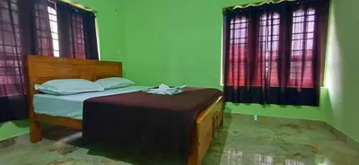 a bedroom with a bed in a green room with windows at Empire HomeStay in Kalpetta