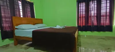 a bed in a green room with two windows at Empire HomeStay in Kalpetta