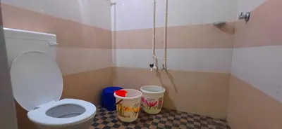 a bathroom with a toilet and two buckets on the floor at Empire HomeStay in Kalpetta