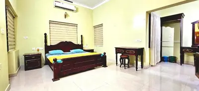 a bedroom with a bed and a table and a desk at KRISHNAGIRI homes in Guruvāyūr
