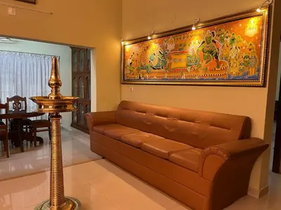 a living room with a couch and a painting on the wall at KRISHNAGIRI homes in Guruvāyūr