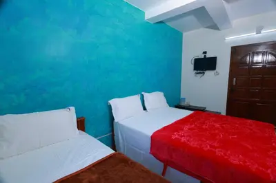 two beds in a room with a blue wall at Seven Endue Cottages in Ooty
