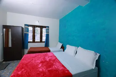 a bedroom with two beds and a blue wall at Seven Endue Cottages in Ooty