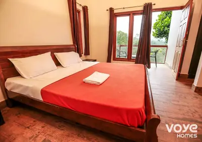 a bedroom with a large bed with a red blanket at Chandragiri Heritage Bungalow and Cottages in Vaduvanchal
