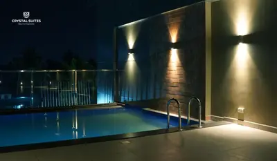 a swimming pool with lights on the side of a building at Crystal Suites in Badagara