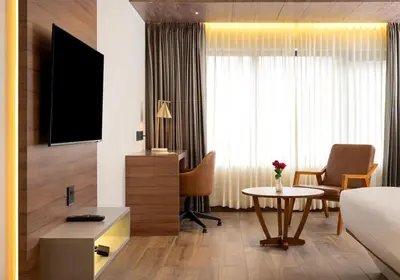 a hotel room with a bed and a desk and a table at Crystal Suites in Badagara