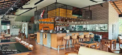 a restaurant with a bar with wooden tables and chairs at PEARL MAHE in Mahe