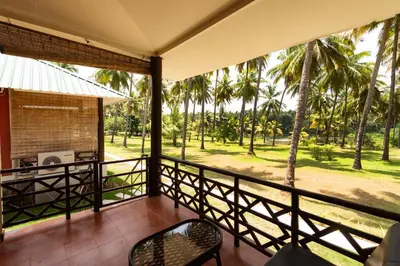 a view from the balcony of a resort with palm trees at Ibex River Resort, Pollachi in Coimbatore