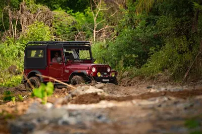 a red jeep driving down a dirt road at Ibex River Resort, Pollachi in Coimbatore