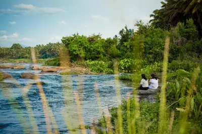 two women sitting on the bank of a river at Ibex River Resort, Pollachi in Coimbatore
