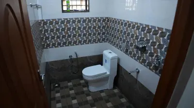 a bathroom with a toilet and a tiled wall at Thas apartment near rajagiri hospital in Alwaye