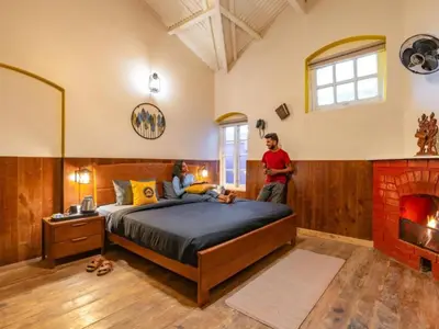 two people in a bedroom with a bed and a fireplace at The Hosteller Ooty in Ooty