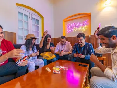 a group of people sitting around a table looking at their cell phones at The Hosteller Ooty in Ooty
