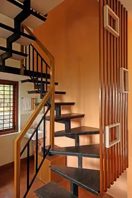 a spiral staircase in a home with wooden railings at Karapuzha Water Scapes Wayanad in Wayanad