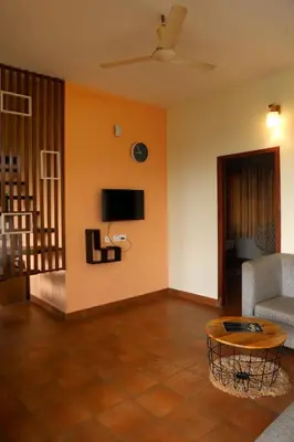 a living room with a couch and a tv on the wall at Karapuzha Water Scapes Wayanad in Wayanad