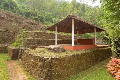 a building with a roof on top of a stone wall at La Grove 2BHK with Stunning View - Kannur in Wayanad