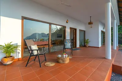 a room with a patio with chairs and a table at La Grove 2BHK with Stunning View - Kannur in Wayanad