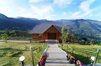 a log cabin with mountains in the background at Vrindhavan Farm Suites in Kanthalloor