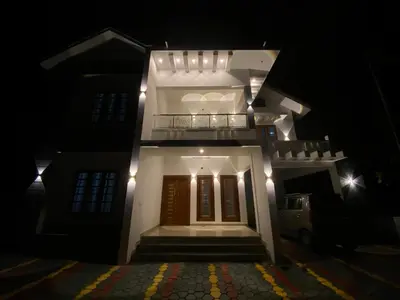 a white house with a balcony at night at HOLLYWOOD Villa in Sultan Bathery