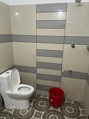 a bathroom with a toilet and a red bucket at HOLLYWOOD Villa in Sultan Bathery