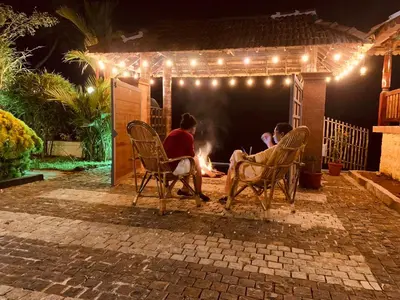 a group of people sitting around a fire at night at CHERAI LAKE RESORT in Cherai Beach