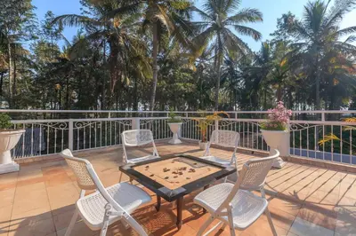a table and chairs on a deck with a game at Bask In The Greens Coorg with Private Pool - Pet Friendly - Complimentary Breakfast in Madikeri
