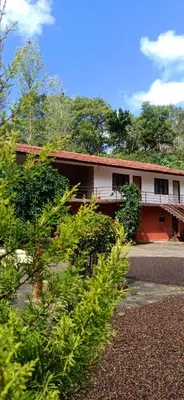 a building with a lot of trees in front of it at Shree Raksha Homestay in Gonikoppal