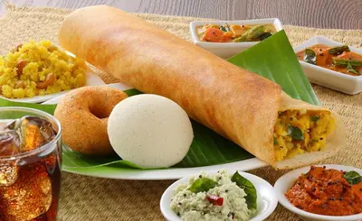 a plate of food with a sandwich on a banana leaf at Chetinaad Courtyard Gandhipuram by Centre Park in Coimbatore