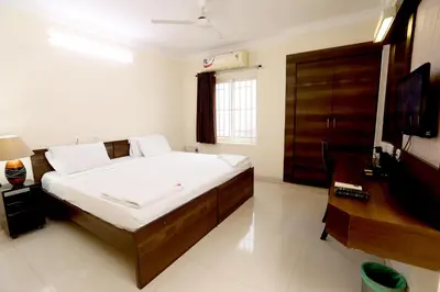 a bedroom with a bed and a desk and a television at Chetinaad Courtyard Gandhipuram by Centre Park in Coimbatore