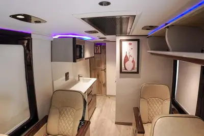 an rv with chairs and a kitchen with purple lights at FRONTLINES CARAVAN in Kadikkād