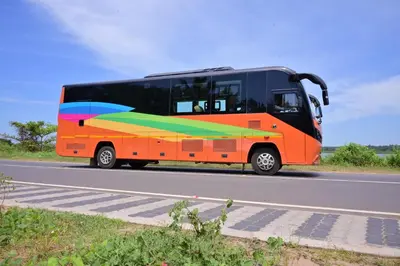 an orange bus with a rainbow painted on the side of the road at FRONTLINES CARAVAN in Kadikkād