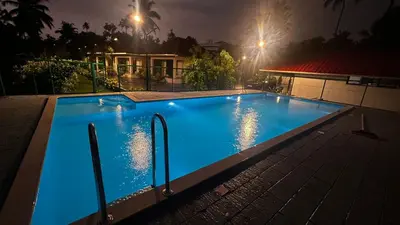 a large blue swimming pool at night with a house at EV StayZ in Cherai Beach