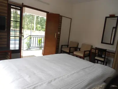 a bedroom with a large white bed and a balcony at EV StayZ in Cherai Beach
