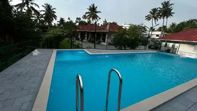 a large blue swimming pool in front of a house at EV StayZ in Cherai Beach