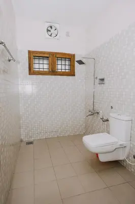 a bathroom with a toilet and a window on the wall at Alite Posh 4 BHK Villa in Thrissur Town in Trichūr