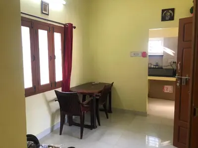 a dining room with a table and chairs in a room at Aishwarya Nivas in Palani