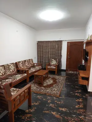 a living room with couches and chairs and a television at Kodai Diva Inn - Home Stay in Kodaikānāl