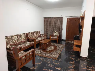 a living room with couches and chairs and a door at Kodai Diva Inn - Home Stay in Kodaikānāl