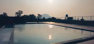 a large pool of water with a mountain in the background at Misty Valley Resort in Varagampadi