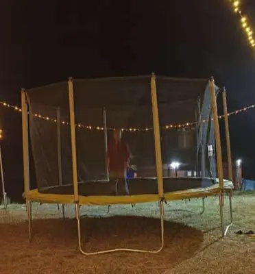 a man standing on a trampoline at night at Misty Valley Resort in Varagampadi