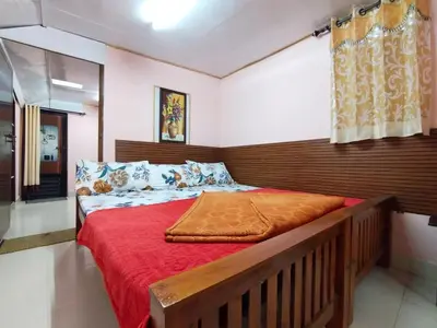 a bedroom with a large bed with a wooden headboard at AKS Home Stay in Munnar