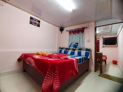 a bedroom with a bed with a red table cloth on it at AKS Home Stay in Munnar