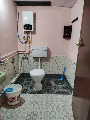 a bathroom with a toilet and a tv on the wall at AKS Home Stay in Munnar
