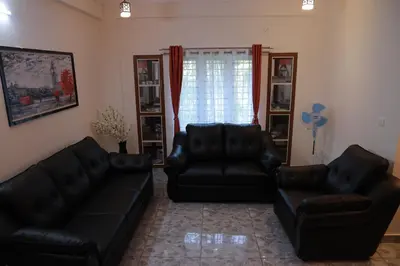 a living room with two black leather couches at AVANTI CASTELLO in Guruvāyūr