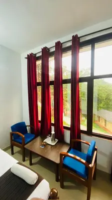 a bedroom with a table and two chairs and a window at Hotel Caveri Inn in Madikeri