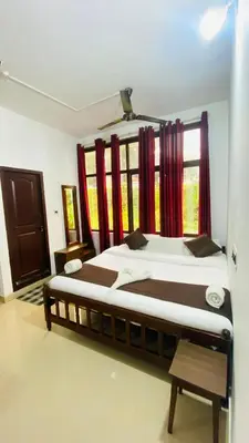 a bedroom with a large bed with red curtains at Hotel Caveri Inn in Madikeri